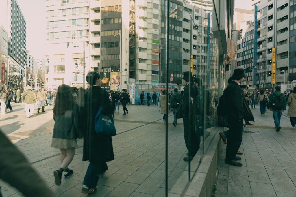 ガラスの反射が重なる東京の街を歩く人々